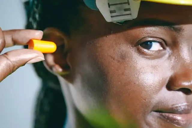 Woman inserting an ear plug on a construction site